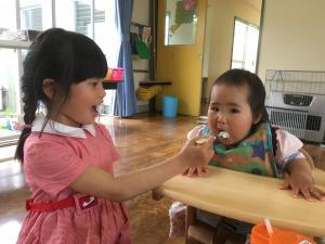 年長さんが小さい子にご飯を食べさせてあげている様子